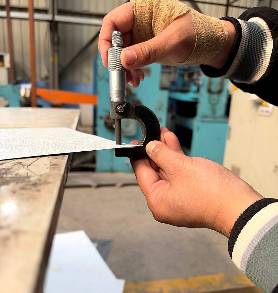 Worker measuring emboss depth with a micrometer, batch by batch